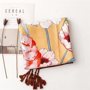 Detailed view of yellow floral scarf with textured fabric and dark brown fringe tassels