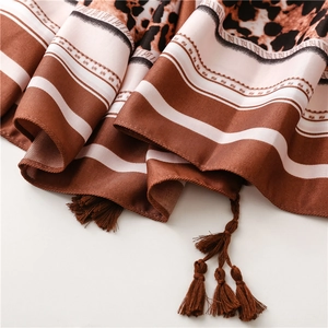 Detail of silk scarf featuring leopard print, brown stripes, and elegant tassels