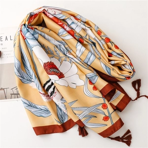 Detailed view of yellow floral silk shawl with delicate tassels and soft fabric texture