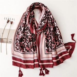 Red leopard print long shawl scarf with tassel trim displayed with magazine and flowers