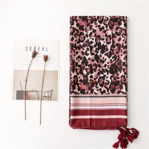 Detail of leopard print silk scarf with red tassels next to decorative magazine props