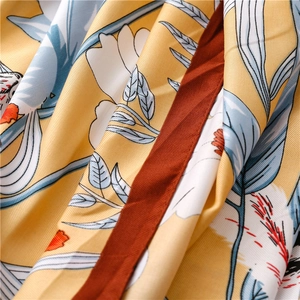Detail of yellow silk scarf with blue floral pattern and subtle twill weave texture