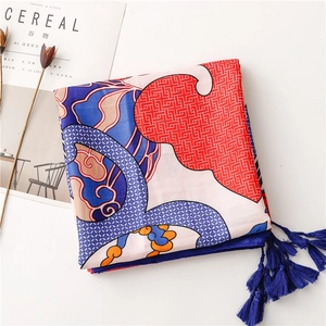 Close-up of ethnic totem silk scarf featuring blue tassels and vibrant geometric prints