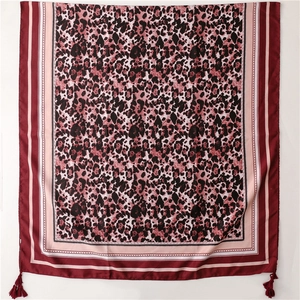 Detail of leopard print silk shawl with wine red border and matching tassel ornaments