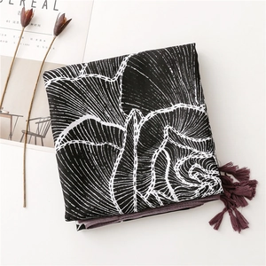 Flat lay of black and white striped scarf with burgundy tassels and decorative dried flowers