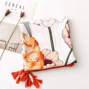 Close-up of floral print scarf featuring orange tassels and botanical patterns