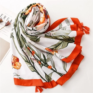 Detail of floral printed scarf with orange tassels and smooth satin texture finish