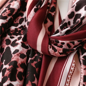 Detail view of leopard print silk scarf with burgundy stripes and soft fabric texture