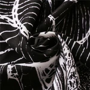 Macro detail of soft black and white ethnic floral print scarf fabric with fringed texture