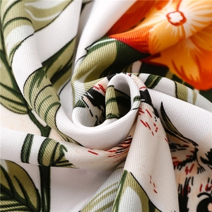 Detailed macro view of tropical floral print fabric with green leaves and orange flowers