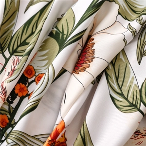 Detail of floral print scarf fabric showing tropical green leaves and orange flowers
