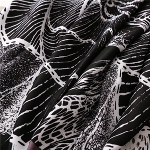Macro shot of black and white leaf print fabric with detailed woven texture and fringes