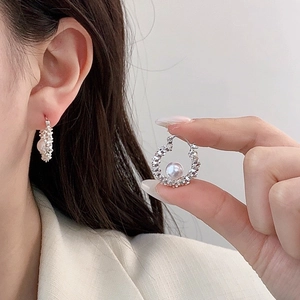 Elegant silver textured hoop earrings featuring round pearl drops worn by a model