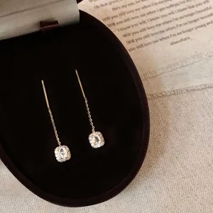 Elegant gold tassel earrings with square zircon clusters on black velvet jewelry box