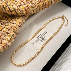 Détail du collier de perles dorées avec fermoir mousqueton réglable et chaîne d'extension
