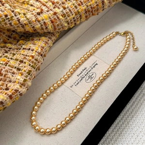 Détail d'un collier de perles dorées élégant avec fermoir réglable dans son coffret à bijoux