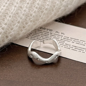 Brushed silver wave ring with five small diamonds on an aesthetic knit background