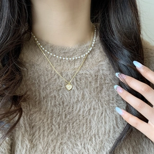Double-layered gold necklace with heart shell pendant and delicate pearl beads