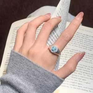Detail of a vintage signet ring with turquoise stone and zircon halo on finger