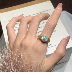 Detailed shot of turquoise ring with gold finish and zircon halo on model hand