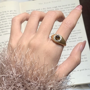 Detailed close-up of a vintage gold ring featuring a brown tiger eye stone and zircon accents