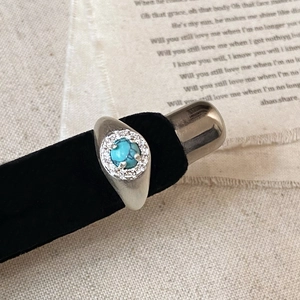 Macro view of vintage silver ring with turquoise stone and zircon halo on black velvet