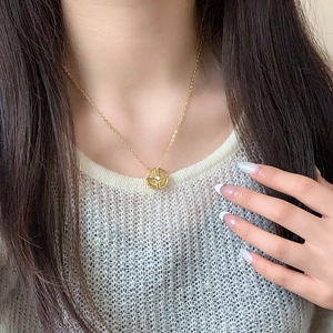 Collier sphère astronomique dorée avec pendentif en zircon porté sur un pull blanc