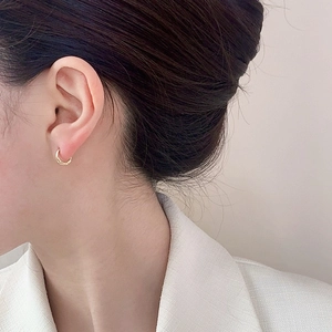 Gros plan d'un mannequin portant des créoles dorées polies au design minimaliste chic