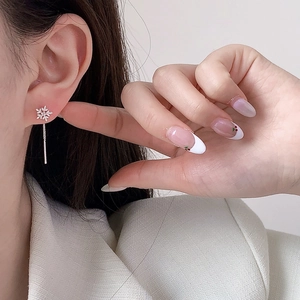 Makroaufnahme eleganter Zirkon-Schneeflocken-Ohrringe mit langer Silberkette am Model