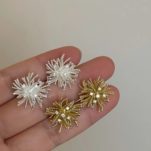 Macro view of gold and silver dandelion stud earrings with sparkling cubic zirconia