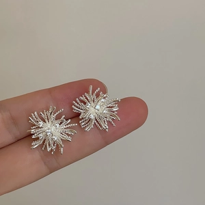Close-up of dandelion zircon studs held by hand to show the actual size and sparkle