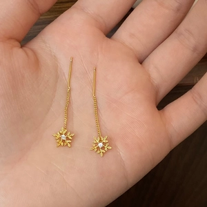 Detailansicht der goldenen Schneeflocken-Ohrhänger mit Zirkonia auf einer Hand