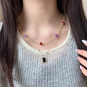 Double-layered gold necklace featuring colorful beads and a black square stone pendant