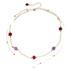 Double-layered gold necklace with red purple beads and small white pearls on white background