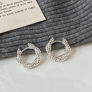 Détail des boucles d'oreilles créoles torsadées en argent avec texture spirale élégante