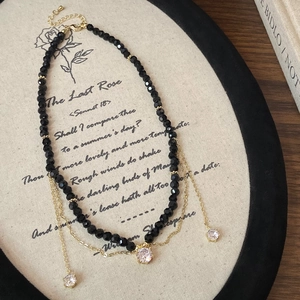 Detailed macro view of black crystal beads and three zircon pendants on a gold chain