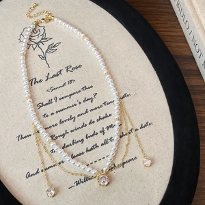 Elegant pearl necklace with gold chain, zircon charms on a vintage floral display