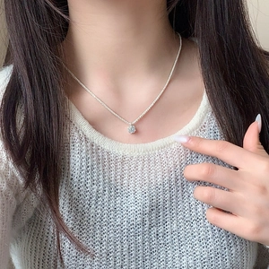 Elegant silver necklace with sparkling round diamond pendant on a model with white knitwear