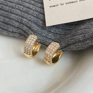 Pave-set cubic zirconia C-shape hoop earrings in 18K gold finish on a knitted texture