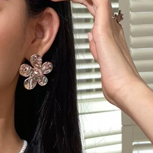 Détail de boucles d'oreilles fleur vintage argentées avec texture martelée sur modèle