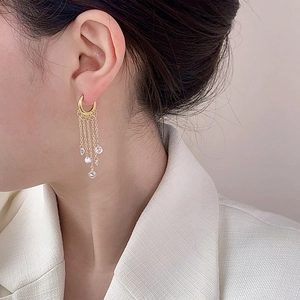 Gold-plated tassel chain earrings with shimmering zircon crystals on a model