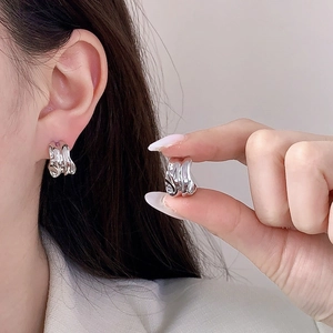 Modern silver irregular liquid metal ear cuffs in C-shape design on female model