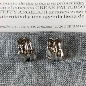 Detailed close-up of silver irregular wave stud earrings with polished mirror finish