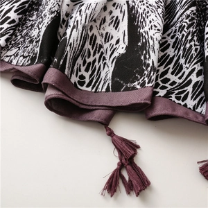 Close-up of beach shawl featuring black ethnic floral patterns and purple tassel details