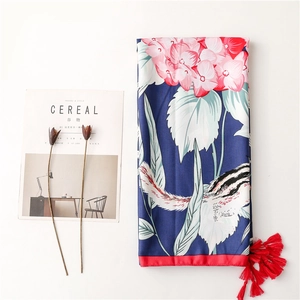 Detail of navy blue silk scarf with pink flowers, squirrels, and red tassel accents