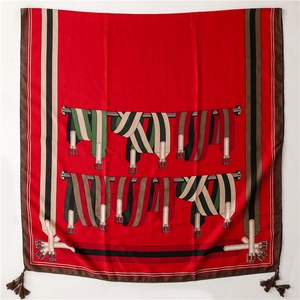 Détail d'un foulard en soie rouge avec motifs équestres et pompons tissés aux coins