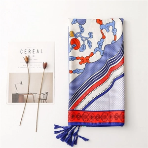 Detail of vibrant silk scarf with ethnic totem prints and elegant blue tassel fringe