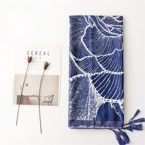 Detail view of navy blue floral silk scarf with fringe tassel and leaf pattern
