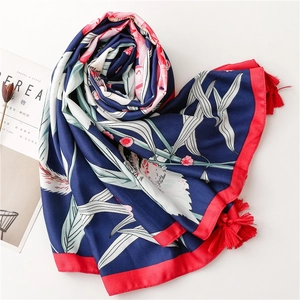 Detailed view of floral silk scarf with red tassels and white crane patterns