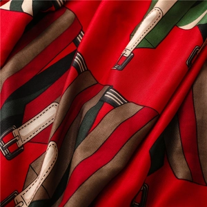 Détail macro d'un foulard en soie rouge avec motifs ceintures et texture sergé